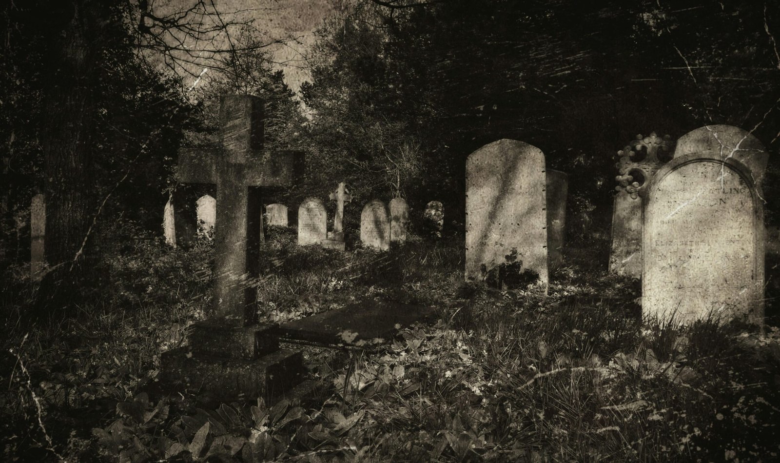 Eerie vintage-style photograph of an old cemetery with gravestones and cross under shadows.