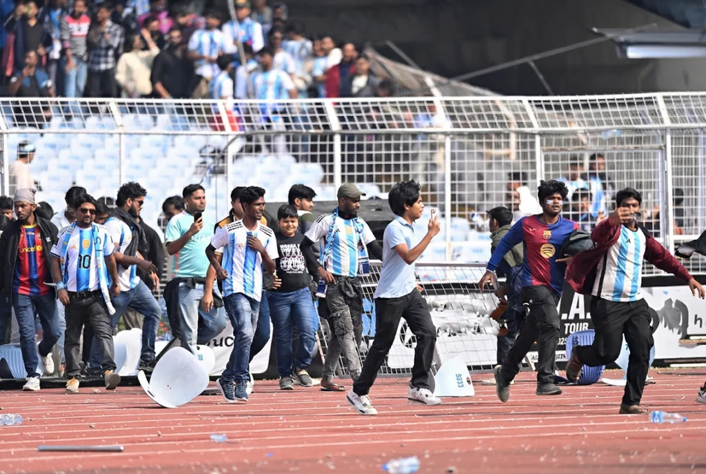 1.	Wide shot of Salt Lake Stadium engulfed in smoke and chaos as fans throw objects onto the pitch during Lionel Messi's visit.