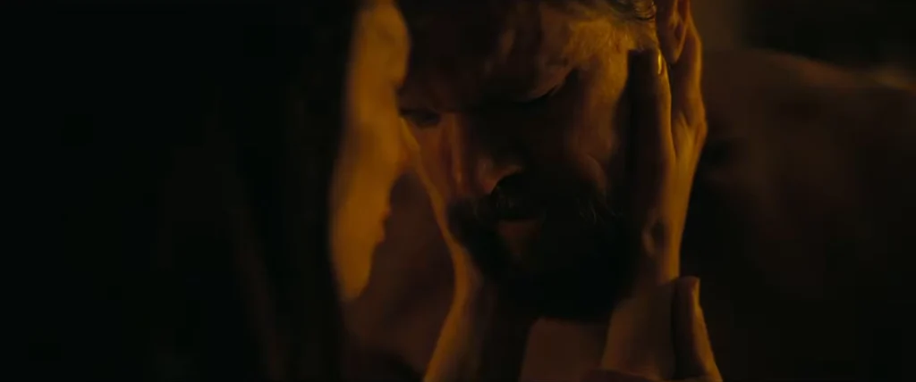 Close-up of Matt Damon with a thick beard and facial scars, looking weary and intense as the character Odysseus.