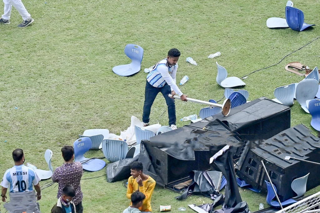 1.	Wide shot of Salt Lake Stadium engulfed in smoke and chaos as fans throw objects onto the pitch during Lionel Messi's visit.